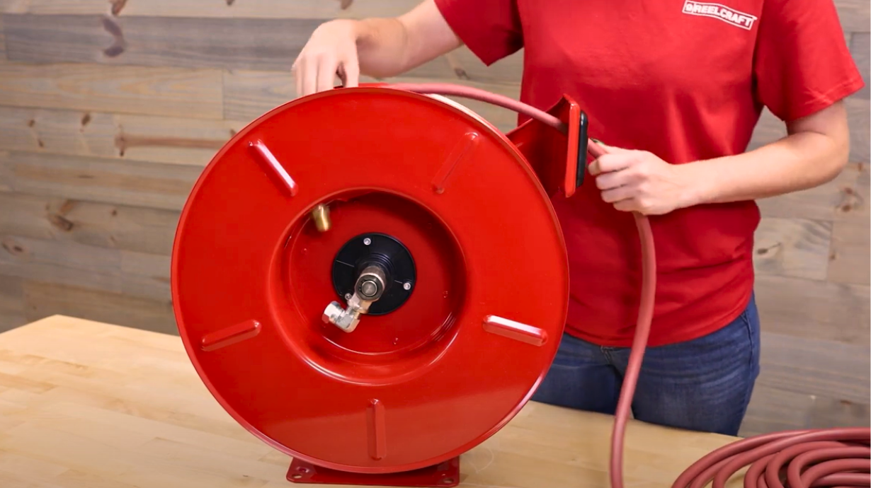 Technician unwinding hose from Reelcraft reel for replacement