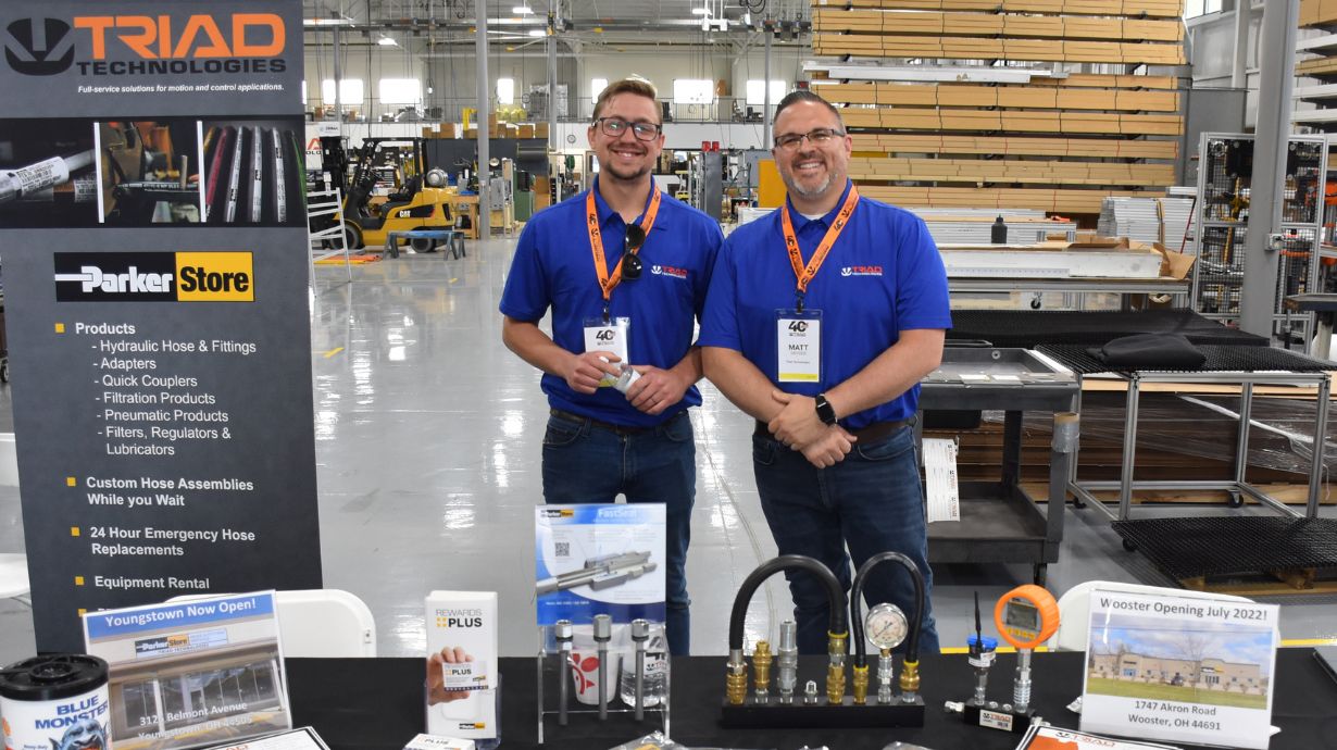 Two Triad employees smiling behind booth at a trade show event